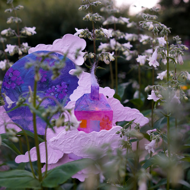 Colorful handmade sculpture among white foxglove flowers